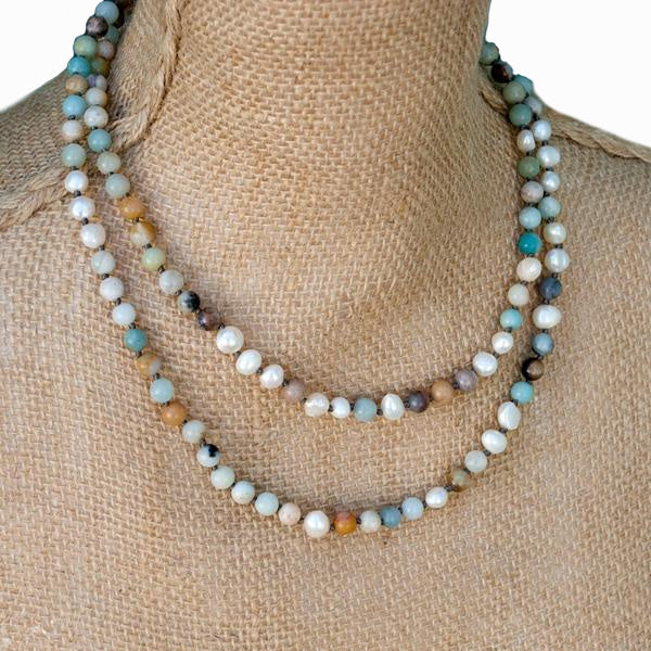  A necklace with hand-knotted white freshwater pearls and matte amazonite beads, displayed doubled on a mannequin.