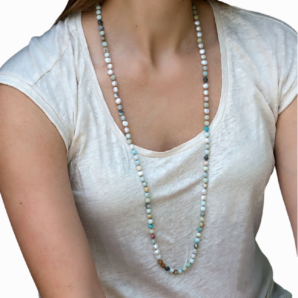 A necklace with hand-knotted white freshwater pearls and matte amazonite beads, shown worn long on a model. 