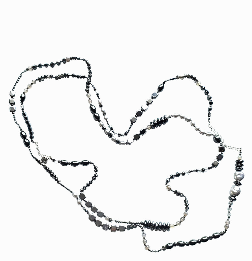 Chic necklace featuring grey freshwater pearls, agate, faceted hematite, and sterling silver is shown on a white background. 