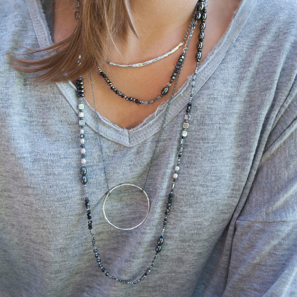 Jet Setter Chic necklace worn long in a layered look with sterling silver necklaces on a model.