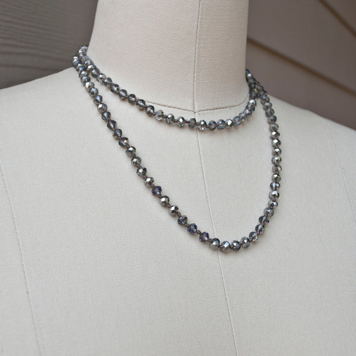 A single-strand, hand-knotted necklace made of faceted aurora borealis crystals is shown worn doubled on a mannequin. 
