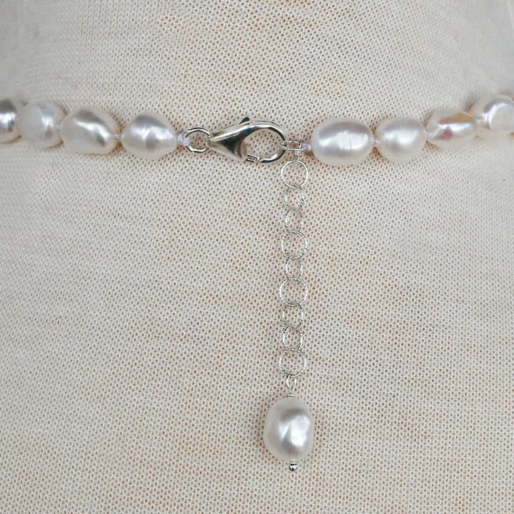 Back view of pearl neckalce is shown with its sterling silver lobster clasp and extender with pearl dangle finishing piece. 