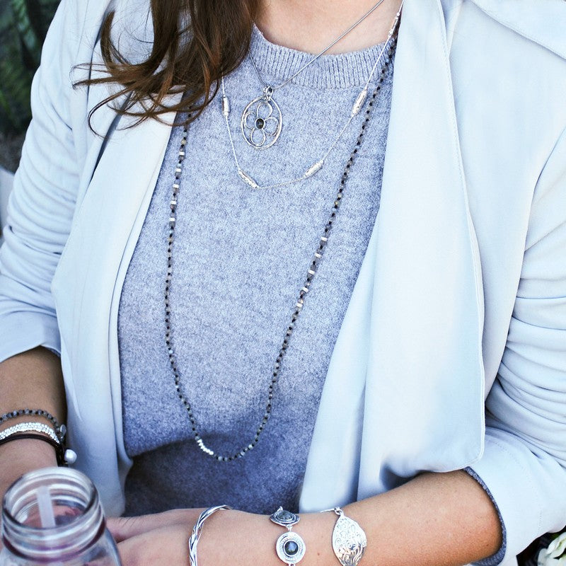 A handknotted labradorite necklace with sterling silver accents is shown on a model worn long. 