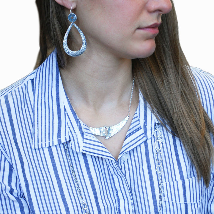 A sterling silver necklace, artisan-crafted, consisting of a sterling chain, a unique silver center link.  Shown on a model.