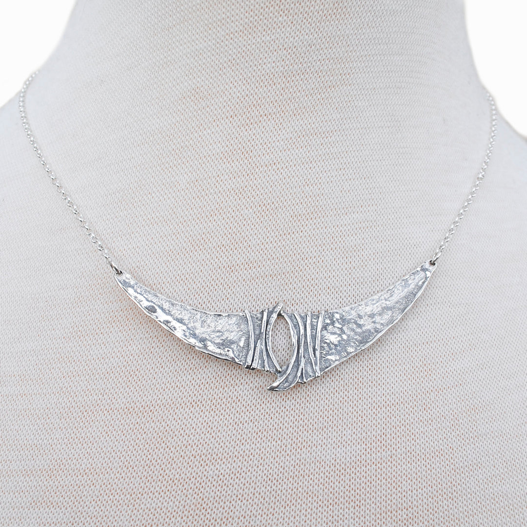A sterling silver necklace, artisan-crafted, consisting of a sterling chain, a unique silver center link.  Shown close-up on a mannequin to see details. 