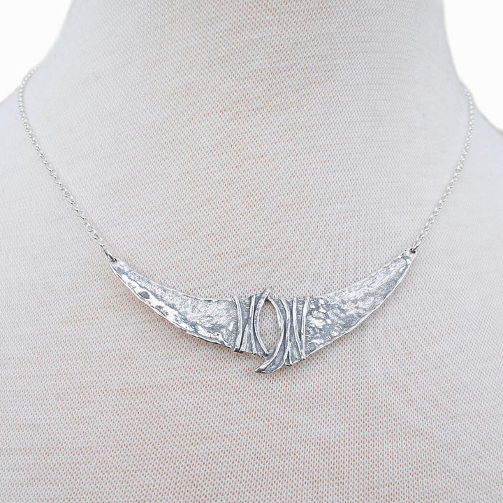A sterling silver necklace, artisan-crafted, consisting of a sterling chain, a unique silver center link.  Shown close-up on a mannequin to see details. 