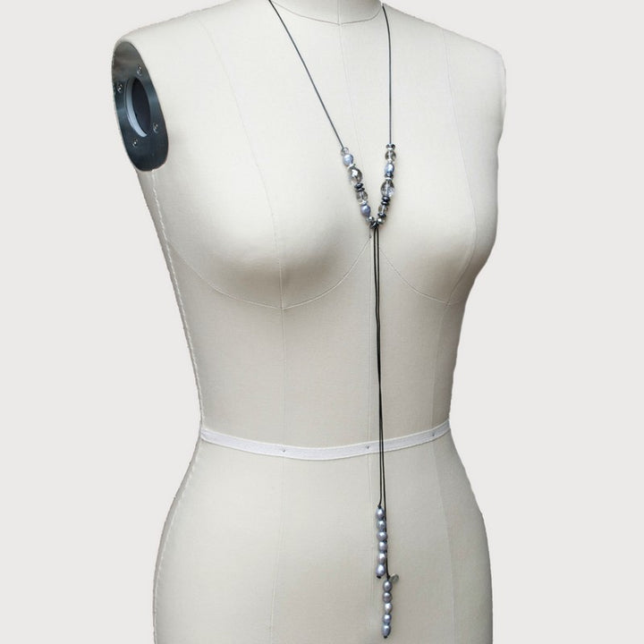 A lariat necklace with gray freshwater pearls, hematite, and crystal, displayed on a mannequin.
