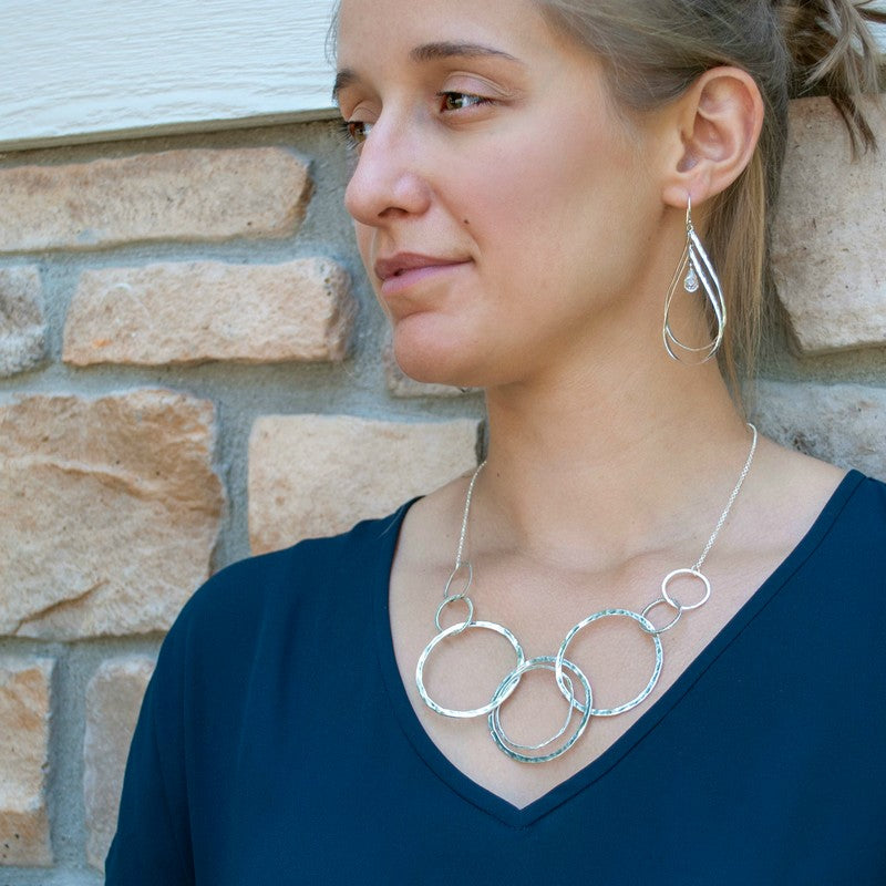 Model wearing the Around We Go sterling silver statement necklace with overlapping circle design.
