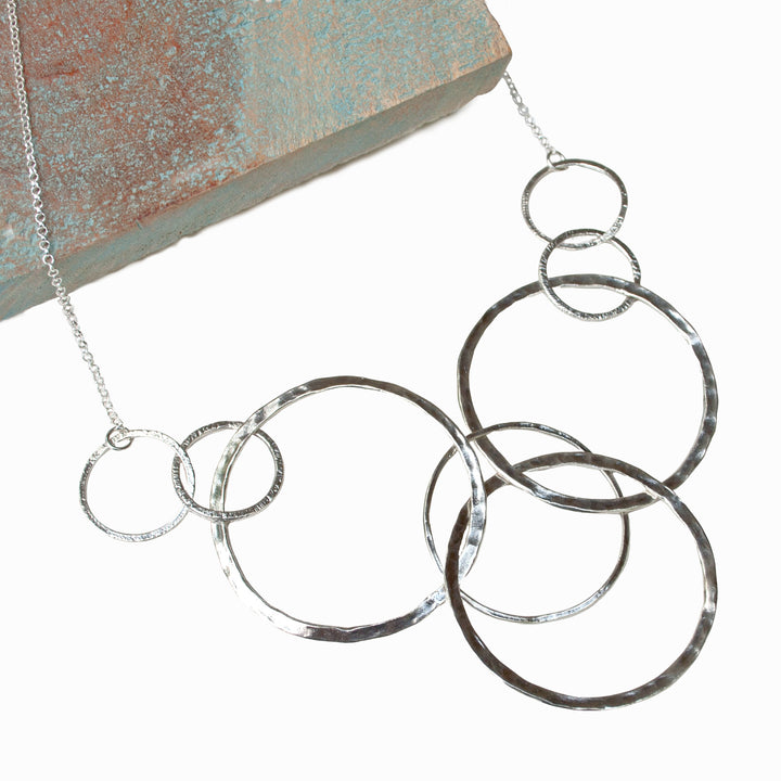 Silver Necklace - sterling silver with 8 various-sized, linked circles displayed on a white background. 