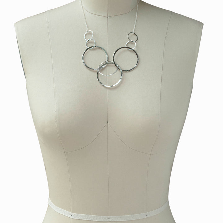 Silver Necklace- Sterling silver with 8 linked circles shown on a mannequin.