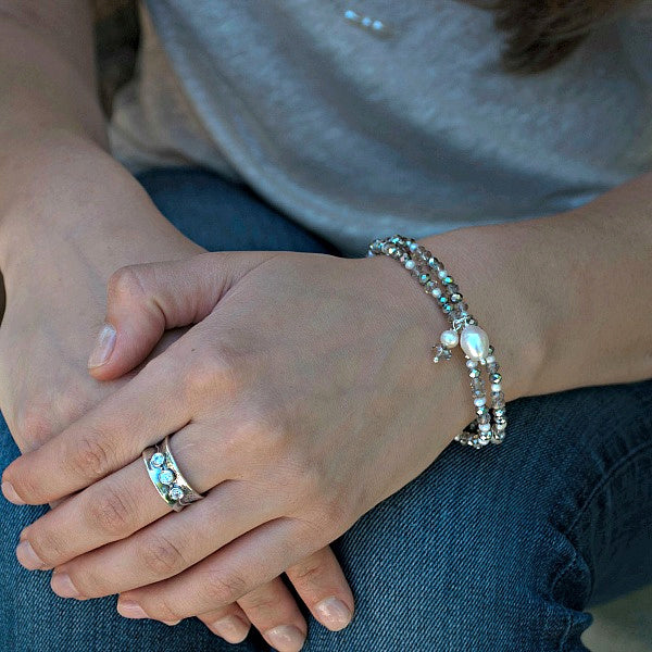 A sterling silver ring with three bezel-set clear cubic zirconia stones in a textured band. Shown on a model. 