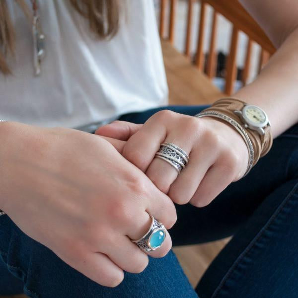 A silver spinner ring with an intricate scroll pattern on a model.