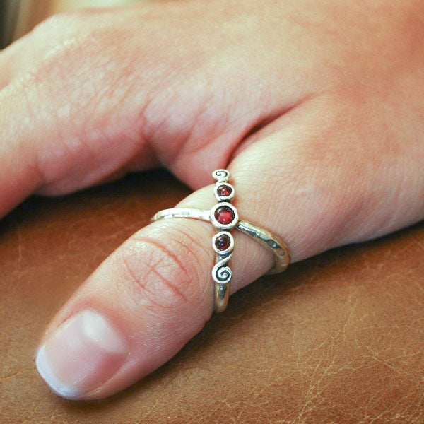 A sterling silver ring with three bezel-set clear cubic zirconia stones in a textured band. Shown on a model. 