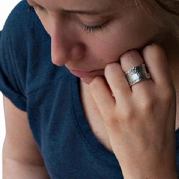 A sterling silver ring with hand-cast vines design, showing intricate patterns around its band. Shown on a model's hand.