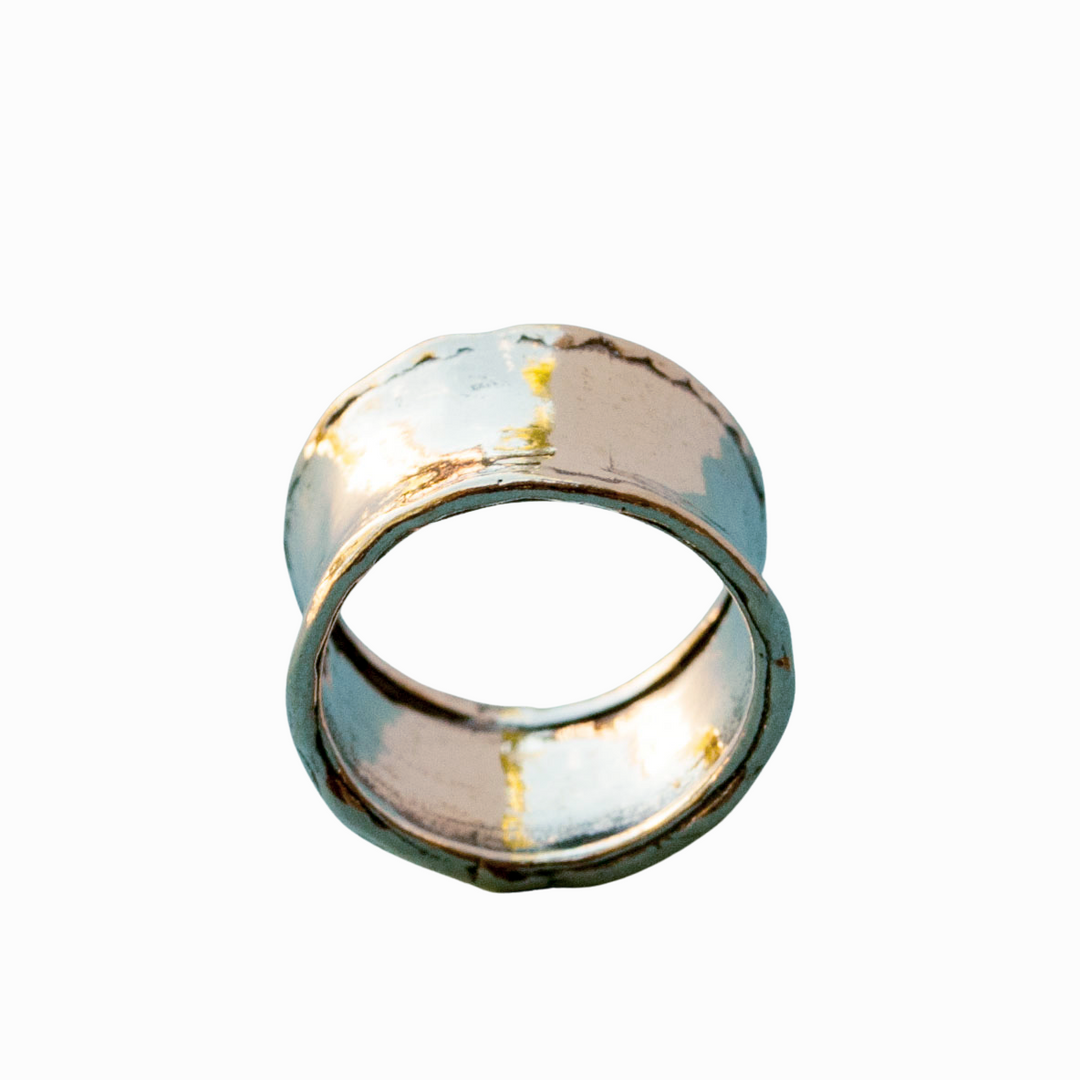 A silver ring with a hammered texture, wide band, and a .925 sterling silver stamp on a white background