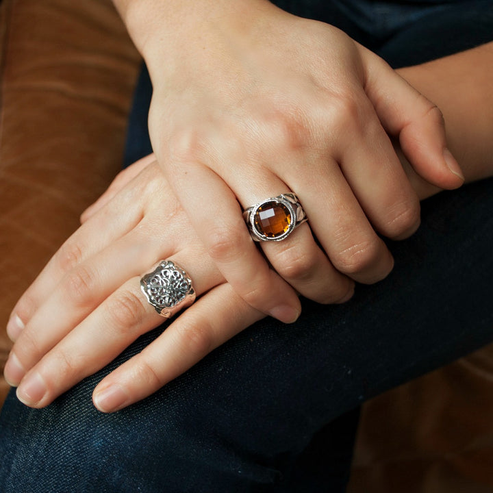 A sterling silver ring with floral lace-like details is shown on a model.  