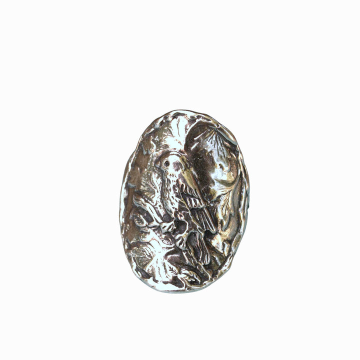 A sterling silver ring with a detailed bird design perched on a branch, showing slight oxidation, is shown from the front on a white background.
