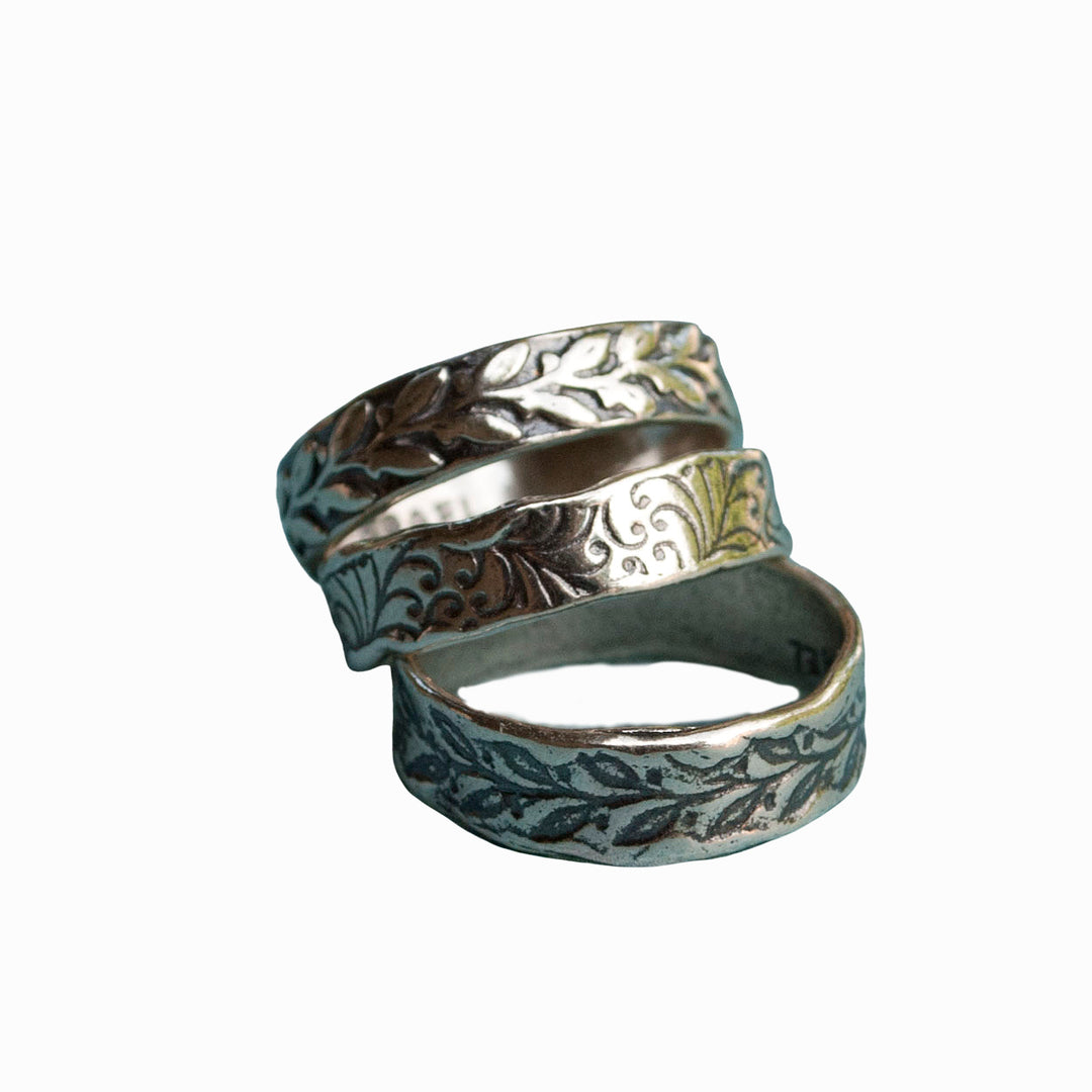 Three sterling silver rings with a floral pattern, stacked together on a white background. 