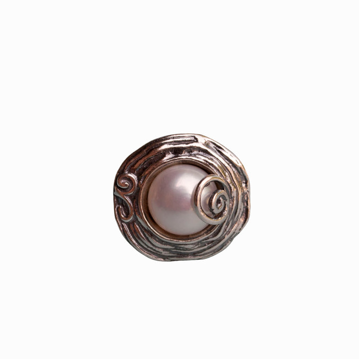 A ring with a freshwater pearl set in a sterling silver band with swirl details is shown on a white background. 