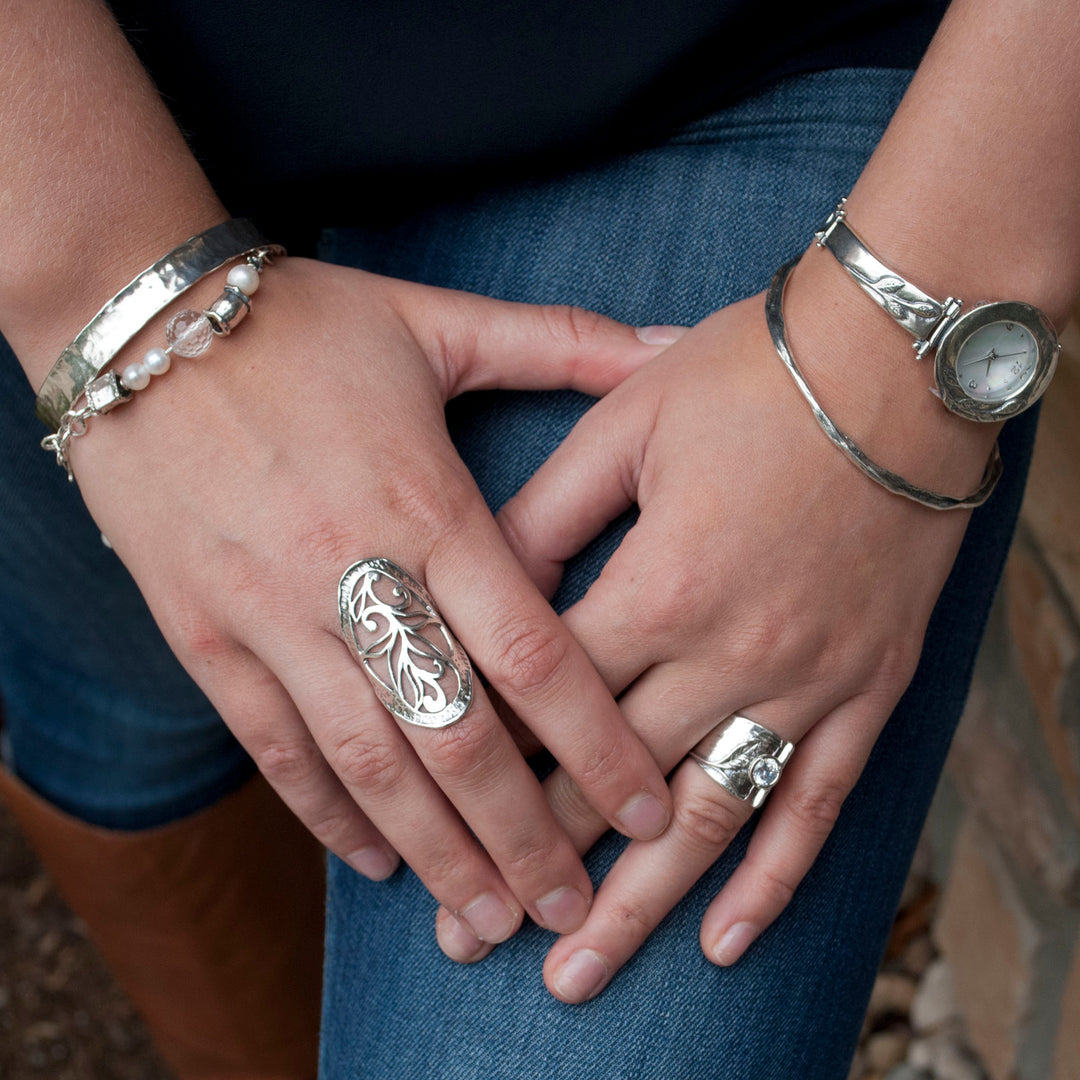 Sterling silver ring with leaf designs and a bezel set round cut clear CZ. Shown on a model's ring finger