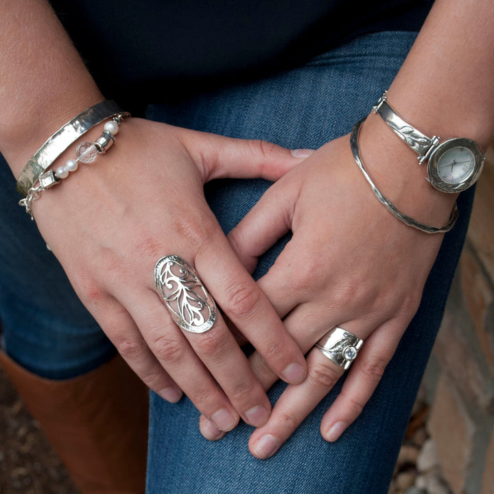 Sterling silver ring with leaf designs and a bezel set round cut clear CZ. Shown on a model's ring finger