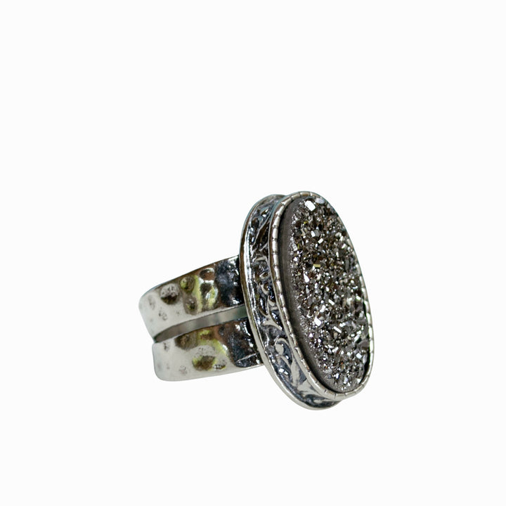 A sterling silver ring with a central oval-shaped druzy quartz stone, featuring a double-hammered band and a comfort fit design. It is shown on a white background. 