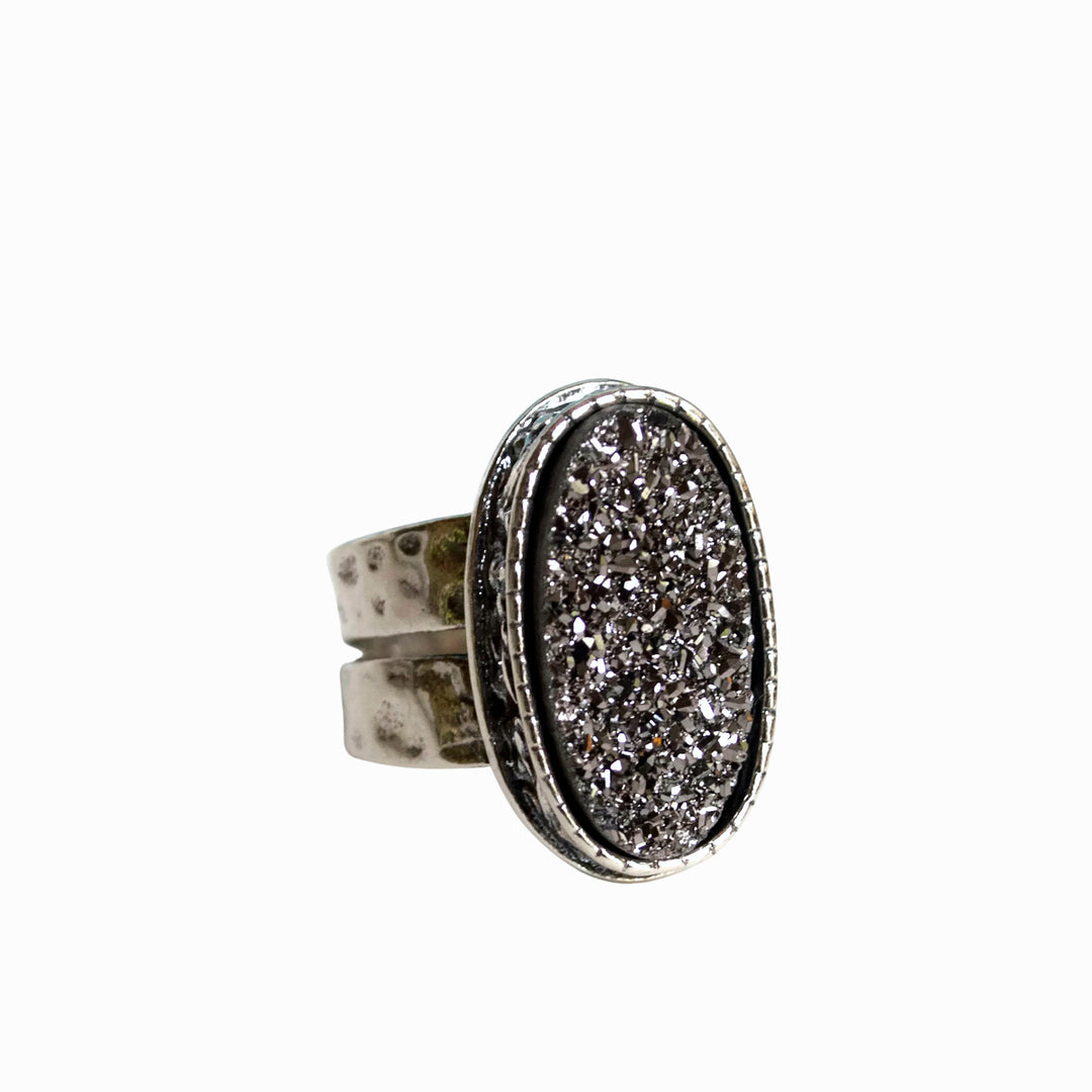 A sterling silver ring with a central oval-shaped druzy quartz stone, featuring a double-hammered band and a comfort fit design. It is shown close-up on a white background. 