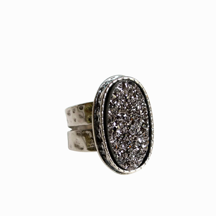 A sterling silver ring with a central oval-shaped druzy quartz stone, featuring a double-hammered band and a comfort fit design. It is shown close-up on a white background. 