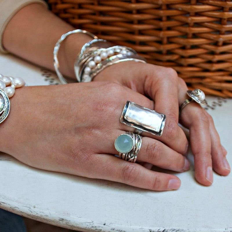 A sterling silver ring with a faceted aqua chalcedony dome on a chunky band, displayed on a model.