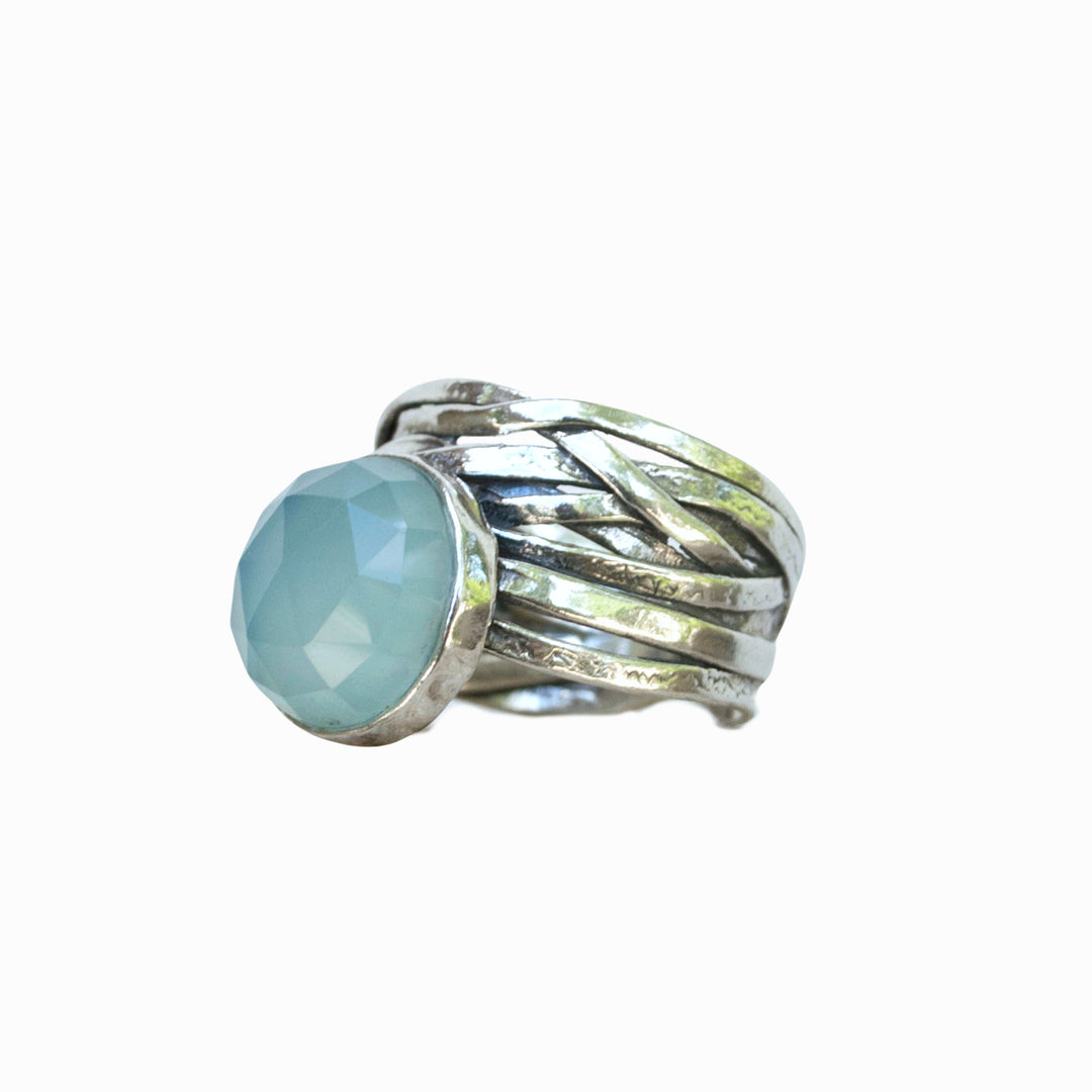 A sterling silver ring with a faceted aqua chalcedony dome on a chunky band, a side view is shown on a white background.