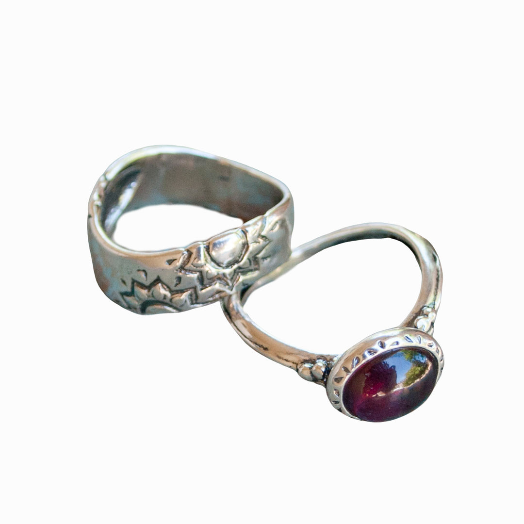 Two sterling silver rings, one with a garnet stone, displayed against a white background.
