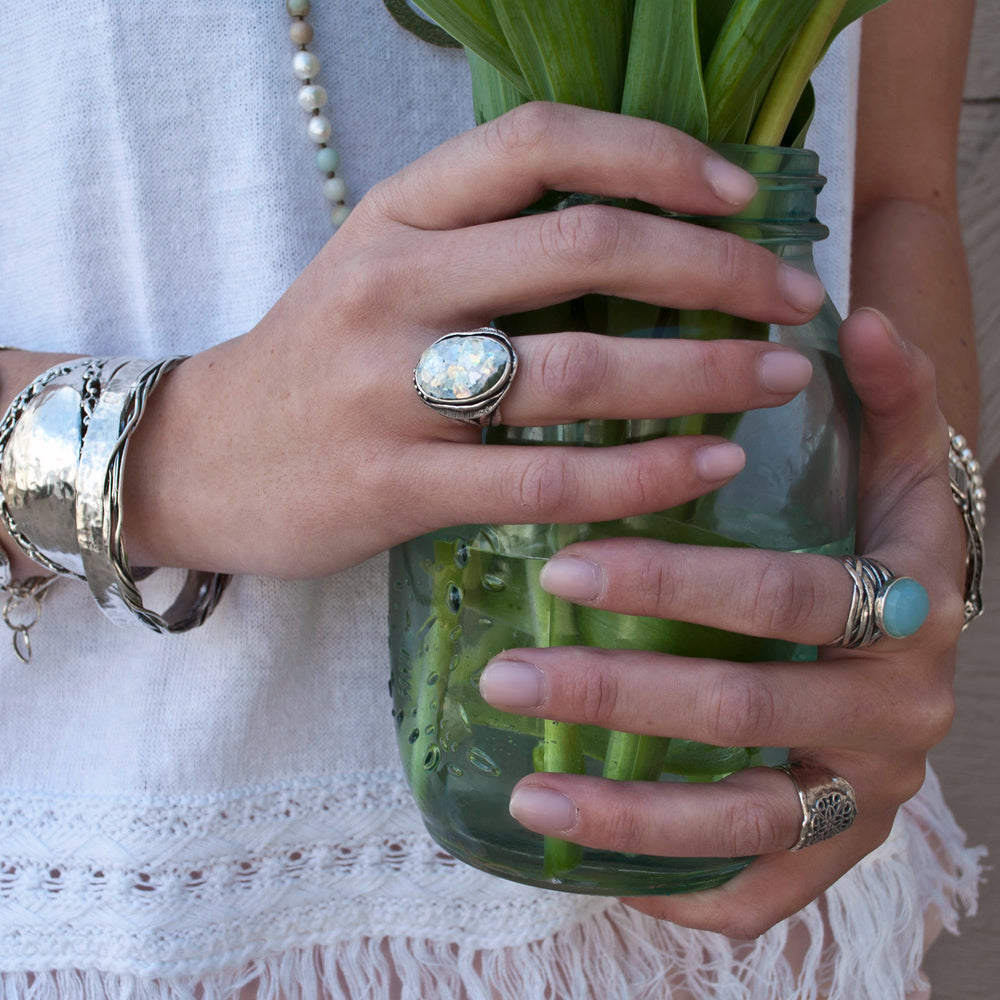 An oval-shaped Roman glass ring with intricate dot details, set in a sterling silver band. Shown on a model.