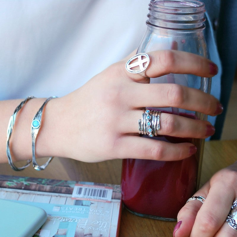 An artisan-crafted hammered sterling silver ring with opal accents is shown on a model.