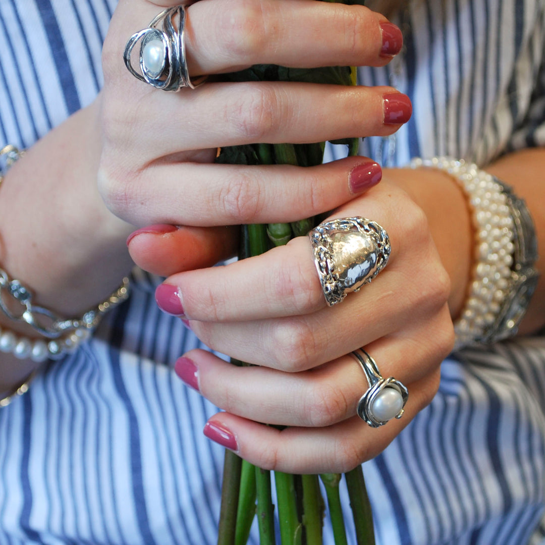 n artisan-crafted sterling silver ring with a freshwater pearl centered amidst swirling silver designs. Shown on a model. 