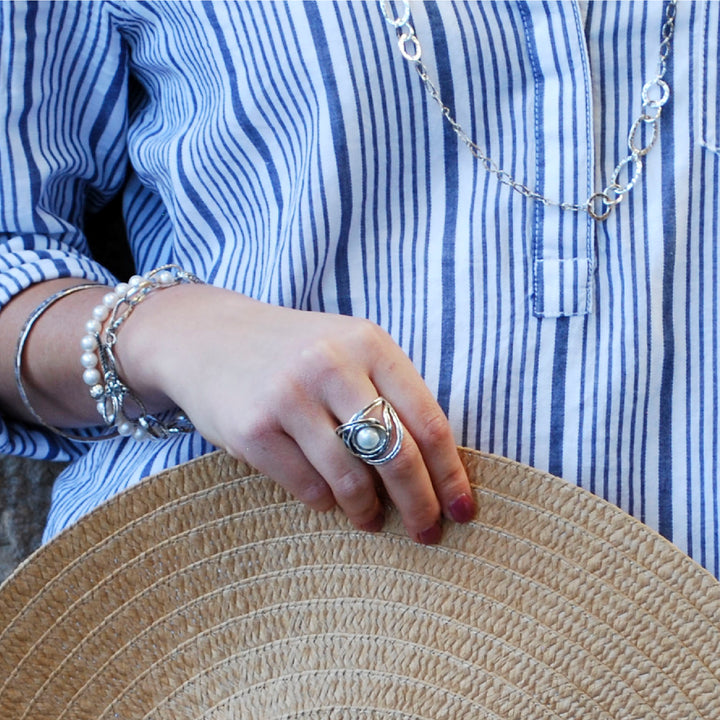 n artisan-crafted sterling silver ring with a freshwater pearl centered amidst swirling silver designs. Shown on a model. 