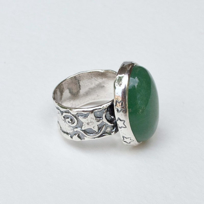 A sterling silver ring with a green adventurine stone set in a setting, featuring detailed work on the band. Side view is shown on a white background. 
