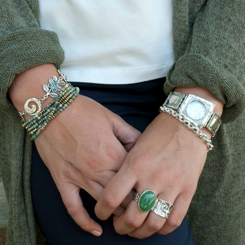 A sterling silver ring with a smooth cabochon of green adventurine stone  is shown on a model. 