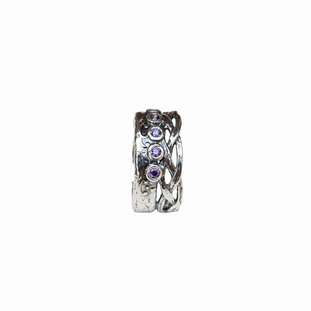 A sterling silver ring with a woven crown detail and bezel-set amethyst CZ stones. A side-view shown on a white background. 