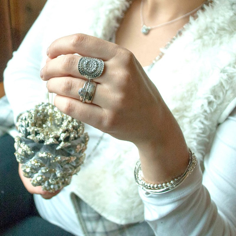 A sterling silver ring with a mandala design, featuring multiple clear cubic zirconia stones. Shown on a model. 