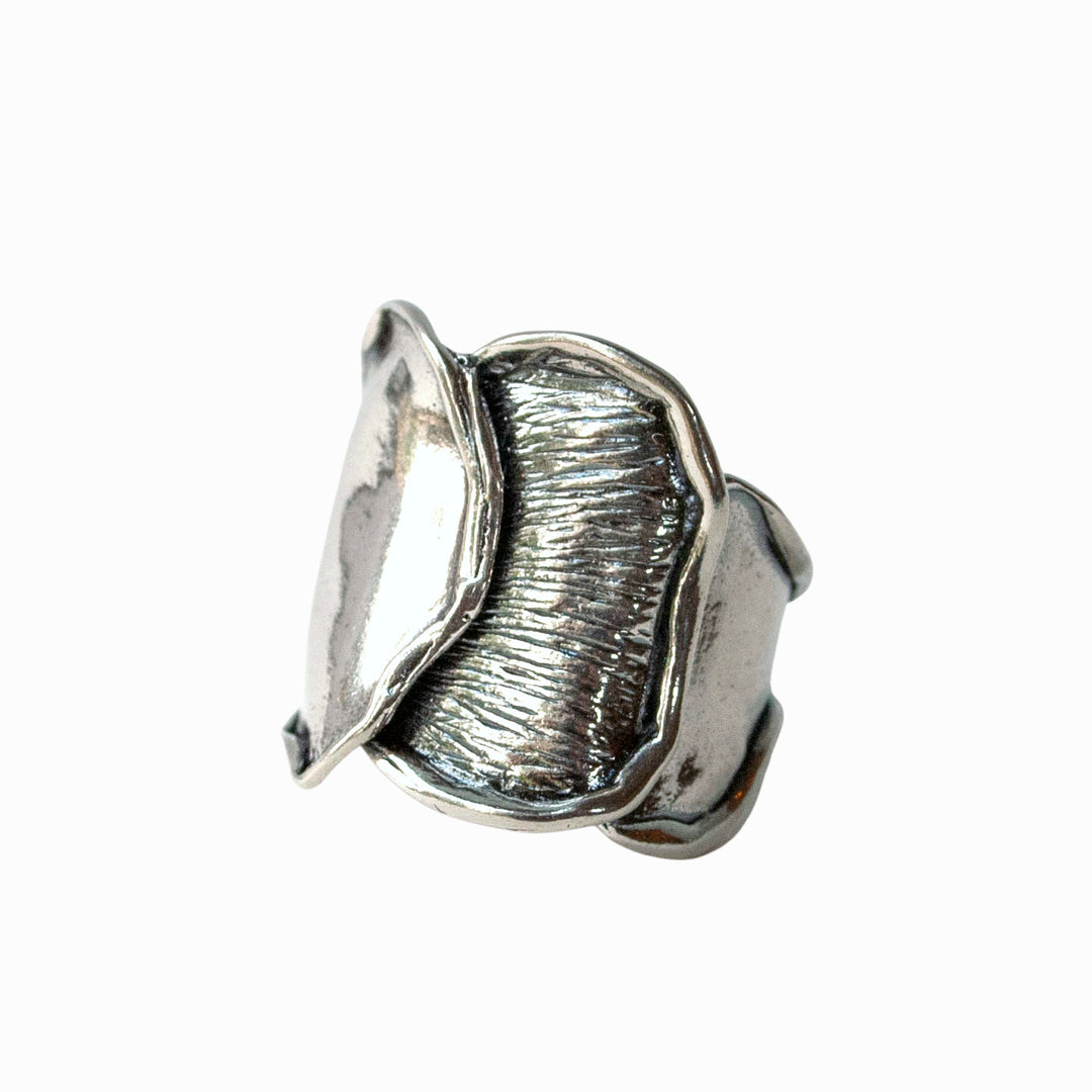 A sterling silver ring with a wave-like design, featuring etched rolled edges and a tapered back. Shown on a white background.