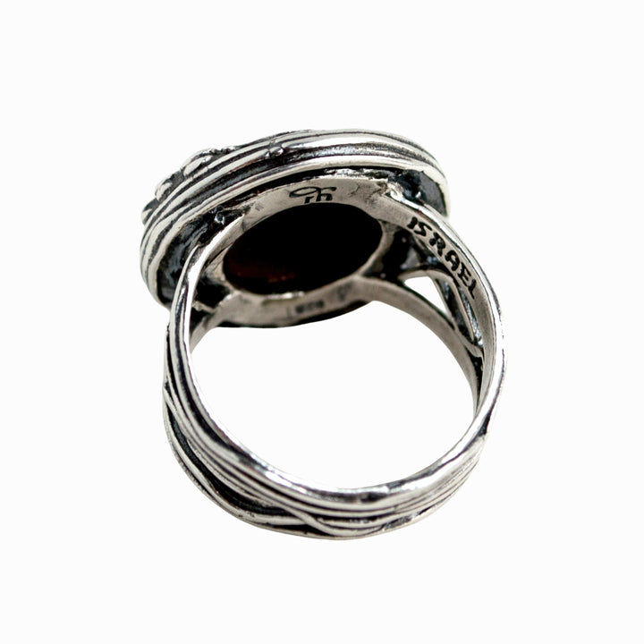 A ring with a gorgeous smooth cabochon of onyx,and a sparkling trio of CZs nestles in a unique setting. Back view is shown on a white background.
