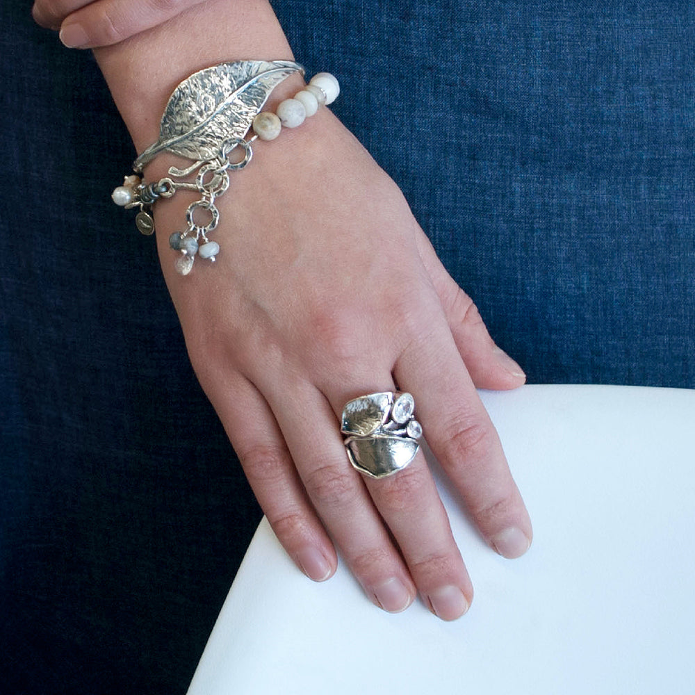 A sterling silver ring with a leaf design and two oval-shaped clear cubic zirconia stones. Shown on a model. 