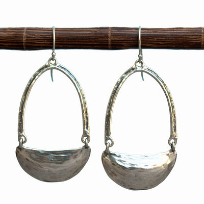 Artisan-crafted sterling silver earrings swing and sway. They measure 2 1/4" long and are shown dangling from a wood piece.