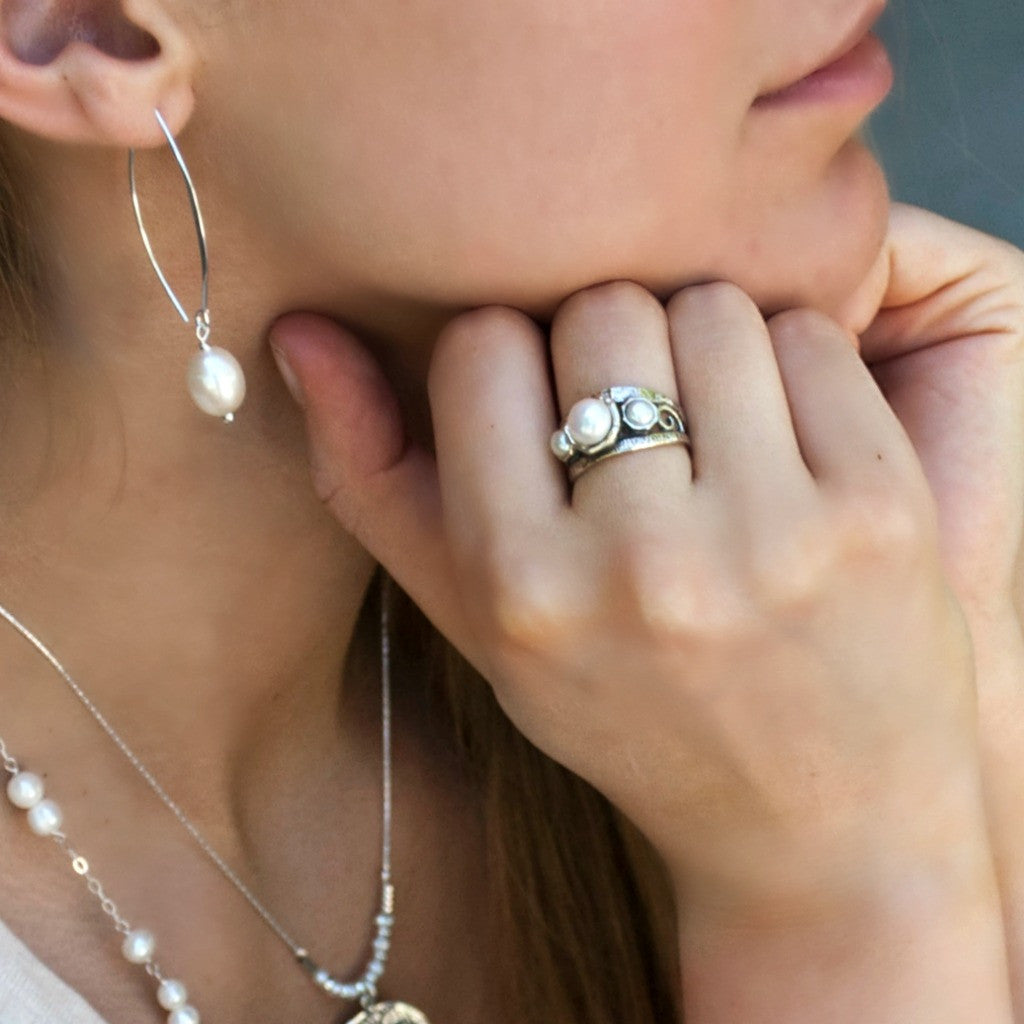 A model wearing a pair of sterling silver and freshwater pearl drop earrings.