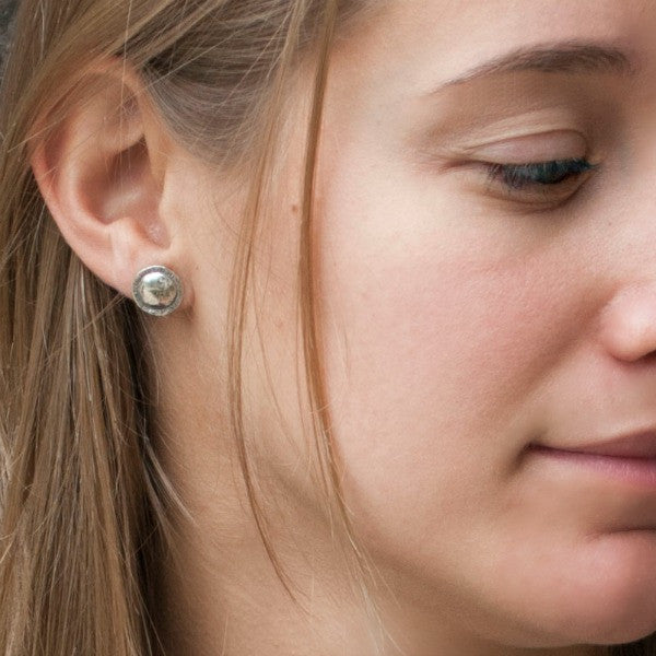 Round-textured sterling silver post earrings are shown on a model.