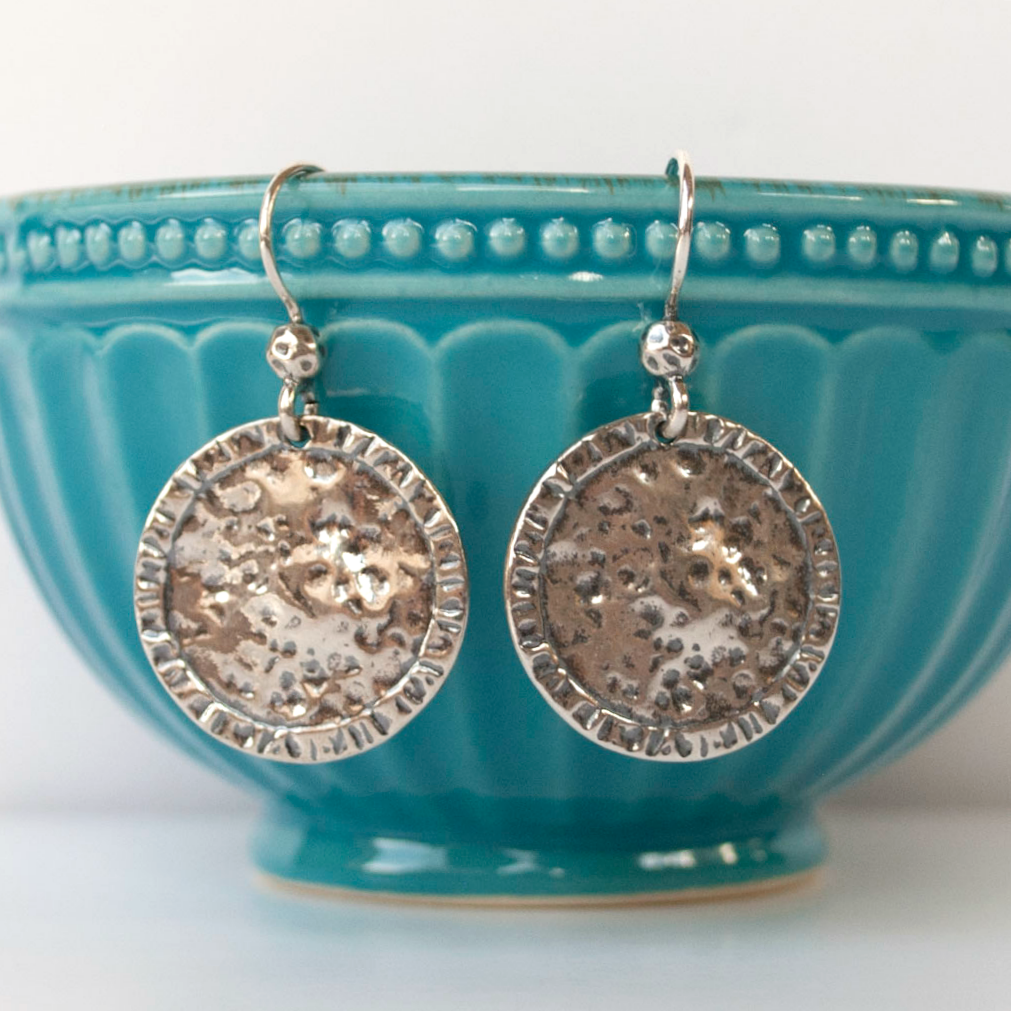 Round, dimpled sterling silver discs drop from French ear wires, displayed dangling on a turquoise bowl.