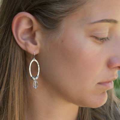 Sterling silver earrings with faceted clear quartz dangles shown on a model.