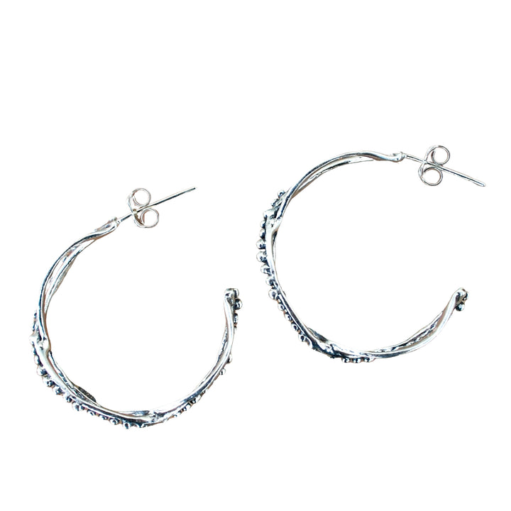 Sterling silver double-hoop earrings feature two distinct hoops, one adorned with tiny beads. Shown on a white background with side view displayed. 