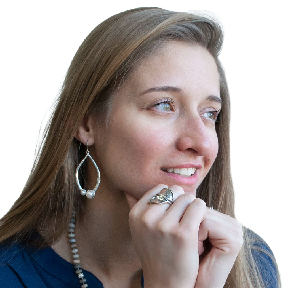 A pair of sterling silver hoop earrings with freshwater pearls attached to them, shown on a model.