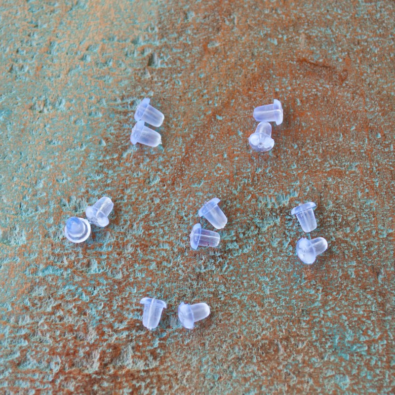 6 pairs of clear plastic earring backs shown on a wood tile. 